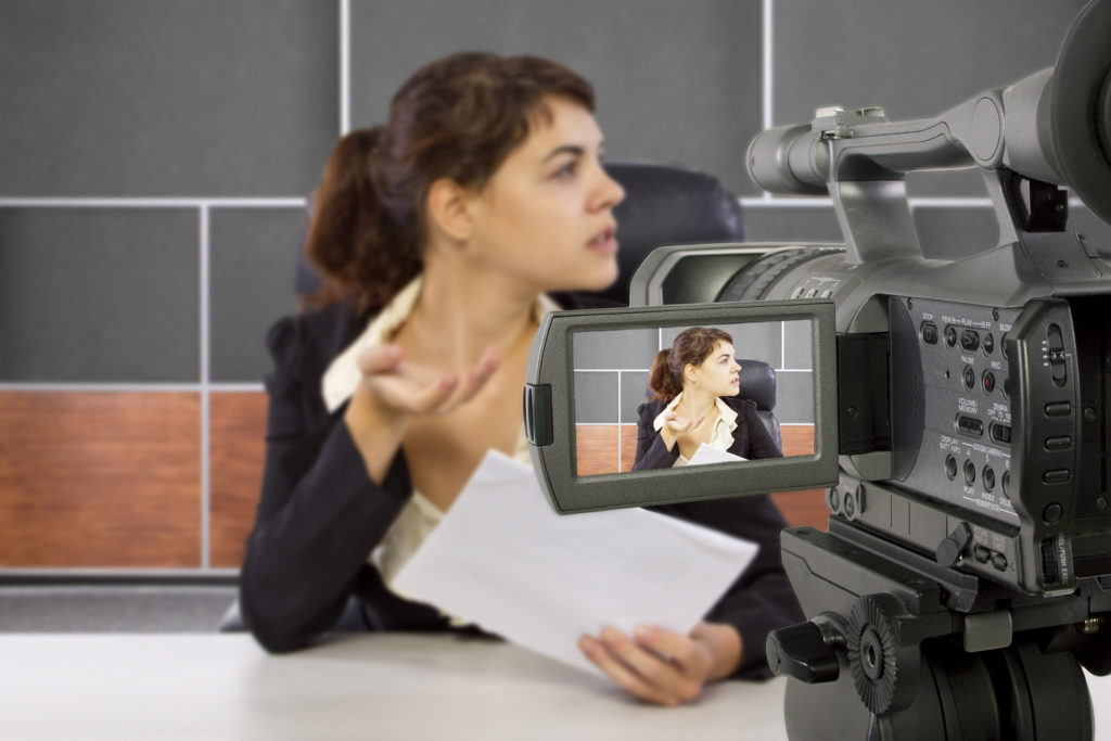 camera view of a female reporter in a news room